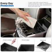 Hand wiping a black waterproof center console organizer tray for easy vehicle maintenance.