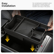 Hands installing a black plastic car center console storage organizer tray.