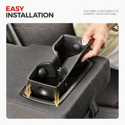Installing a black 4x4 vehicle center console cup holder into a truck seat compartment.