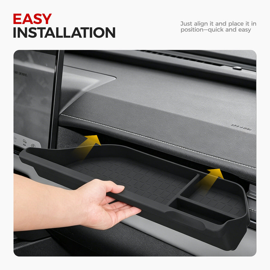 Hand installing a black rubberized car center console organizer tray into a vehicle dashboard.
