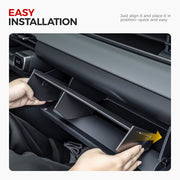 Hands installing a black modular glove box organizer into a vehicle dashboard compartment.