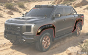 Customized grey 4x4 off-road pickup truck driving through a desert sand dune trail.