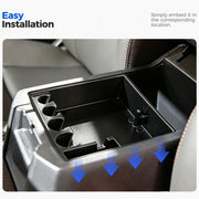 Black plastic vehicle center console organizer being installed into a car interior.