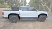 White 4x4 pickup truck with black fender flares and off-road wheels parked on a dirt path.