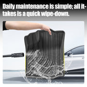 A person cleaning a durable black rubber car floor mat with a high-pressure water spray.