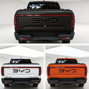 Rear view of BYD Shark 6 pickup trucks in matte black, white, and orange colors.